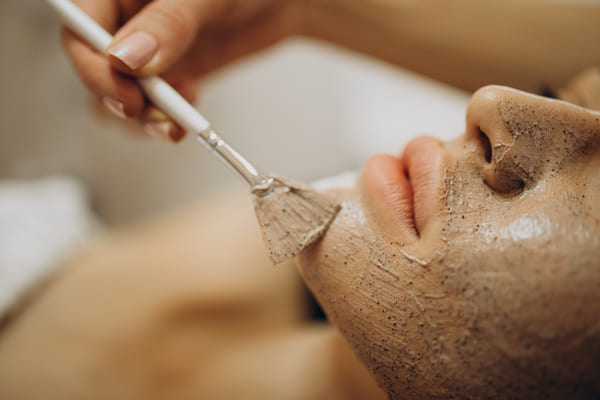 Imagen de una cosmetóloga aplicando un exfoliante facial profesional