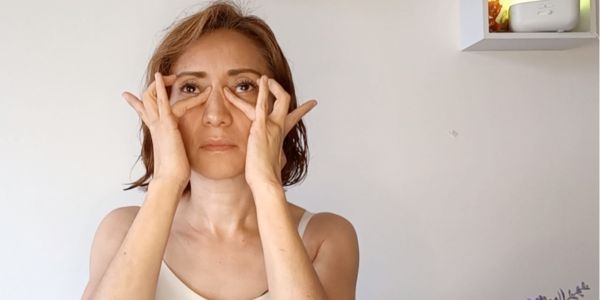 Mujer realizando ejercicios anti envejecimiento de yoga facial