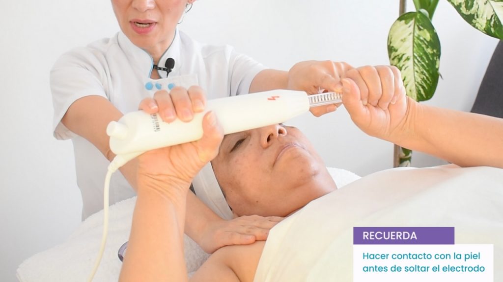 Manos de la terapeuta asegurando el contacto eléctrico antes de comenzar la aplicación del producto.