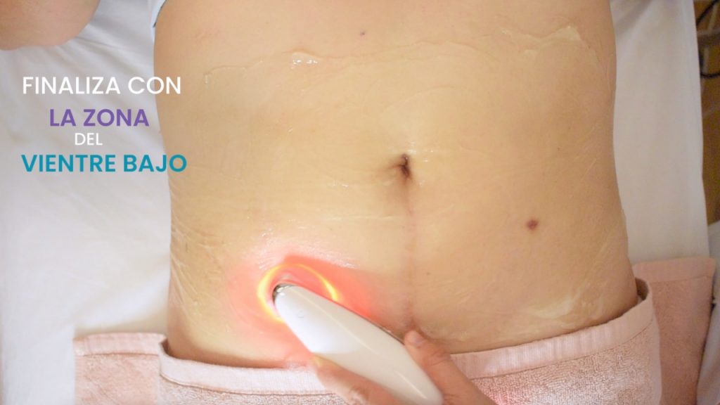 Aparatología estética aplicando tratamiento de reducción de grasa en el vientre bajo con tecnología de luz y gel conductor.