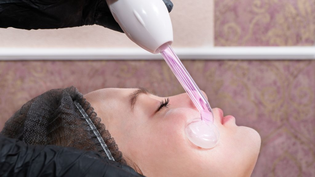 Aparato de alta frecuencia en uso durante un tratamiento facial.