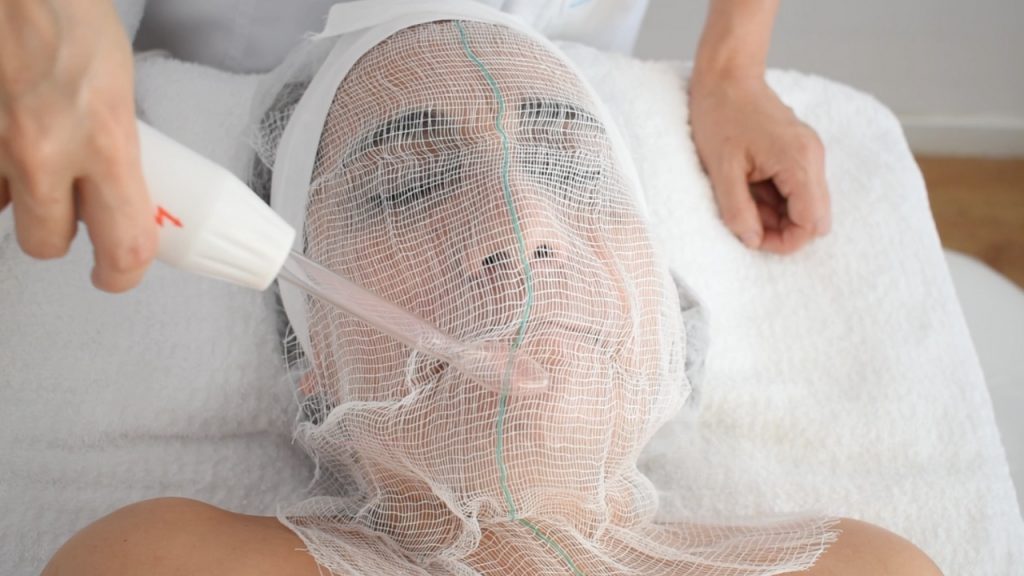 Demostración de la técnica de efluvio con aparato de alta frecuencia facial.