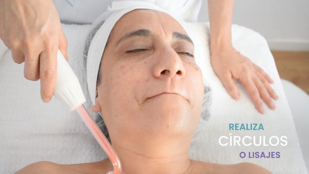 Cosmetóloga aplicando la técnica de chisporroteo durante un tratamiento facial.