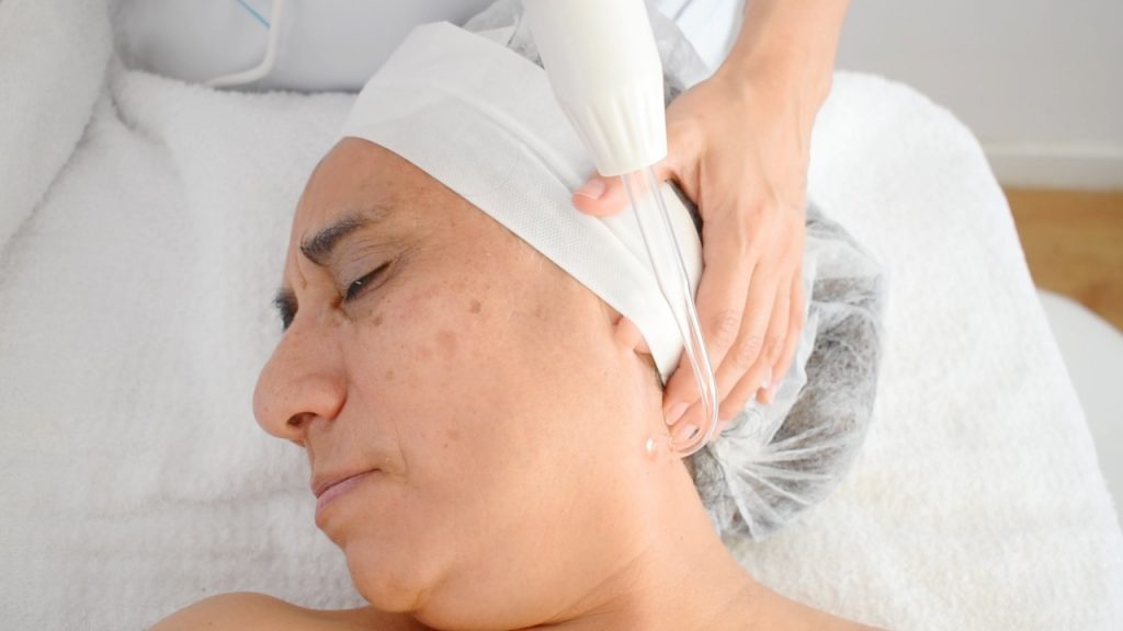 Tratamiento facial con alta frecuencia aplicado por cosmetóloga en cabina estética profesional