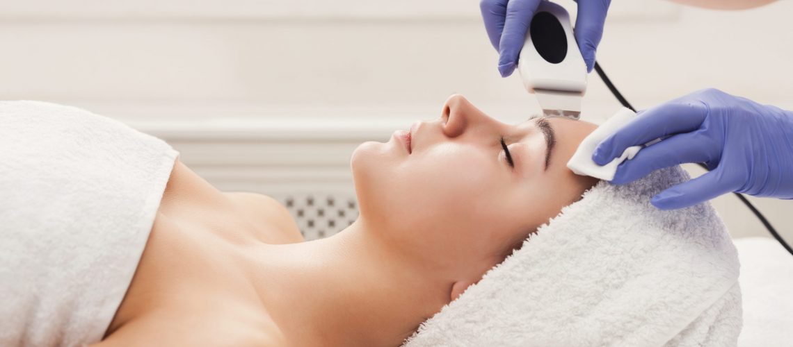 Rejuvenating facial treatment. Model getting lifting therapy massage in a beauty SPA salon. Exfoliation, stimulation and hydratation. Aesthetic cosmetology, closeup, copy space, side view